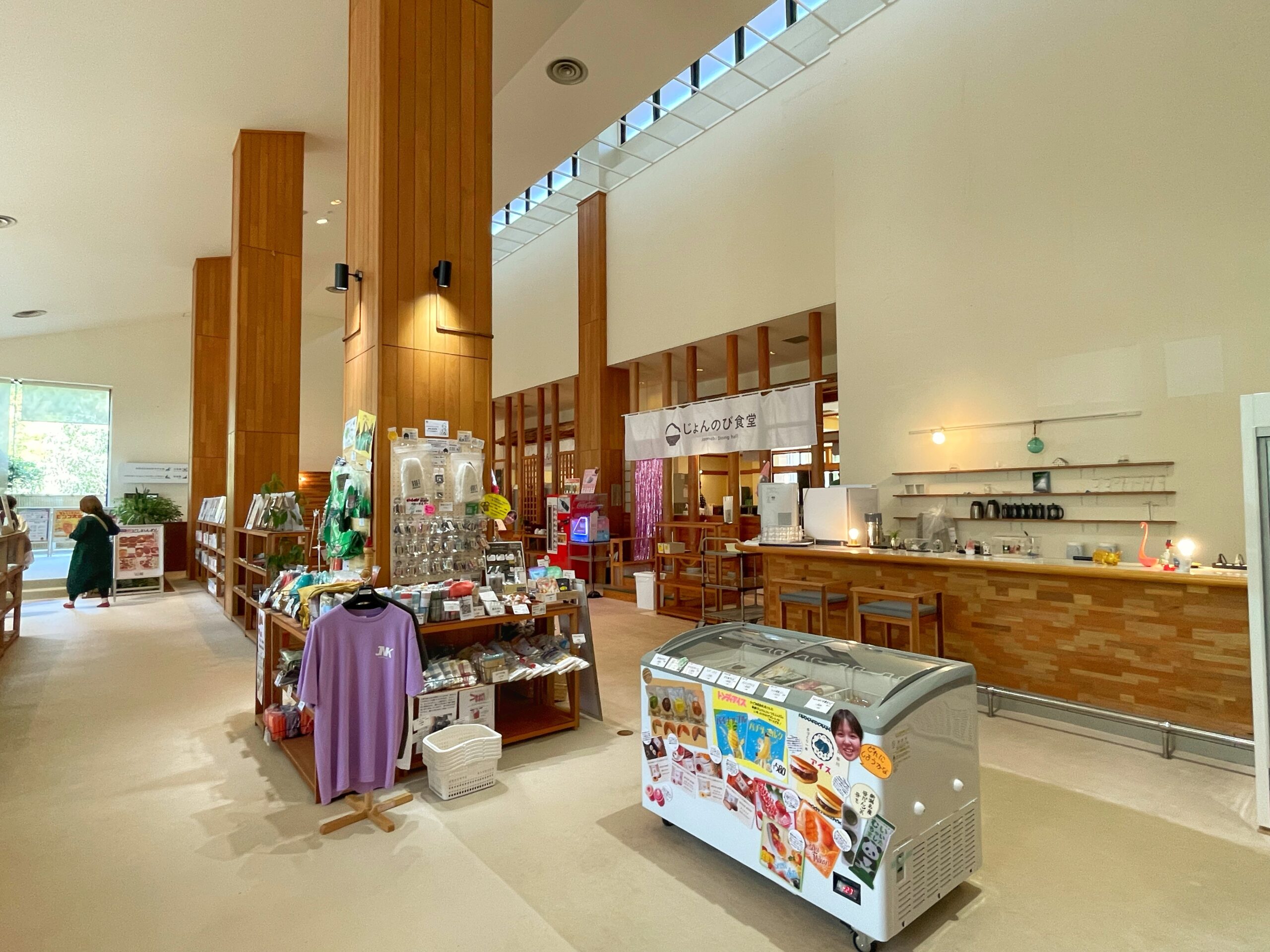 じょんのび館の館内ロビー｜天窓から自然光が差す白壁と木目の広い空間に土産物棚と冷凍ケースが並ぶ物産コーナー｜新潟県新潟市西蒲区