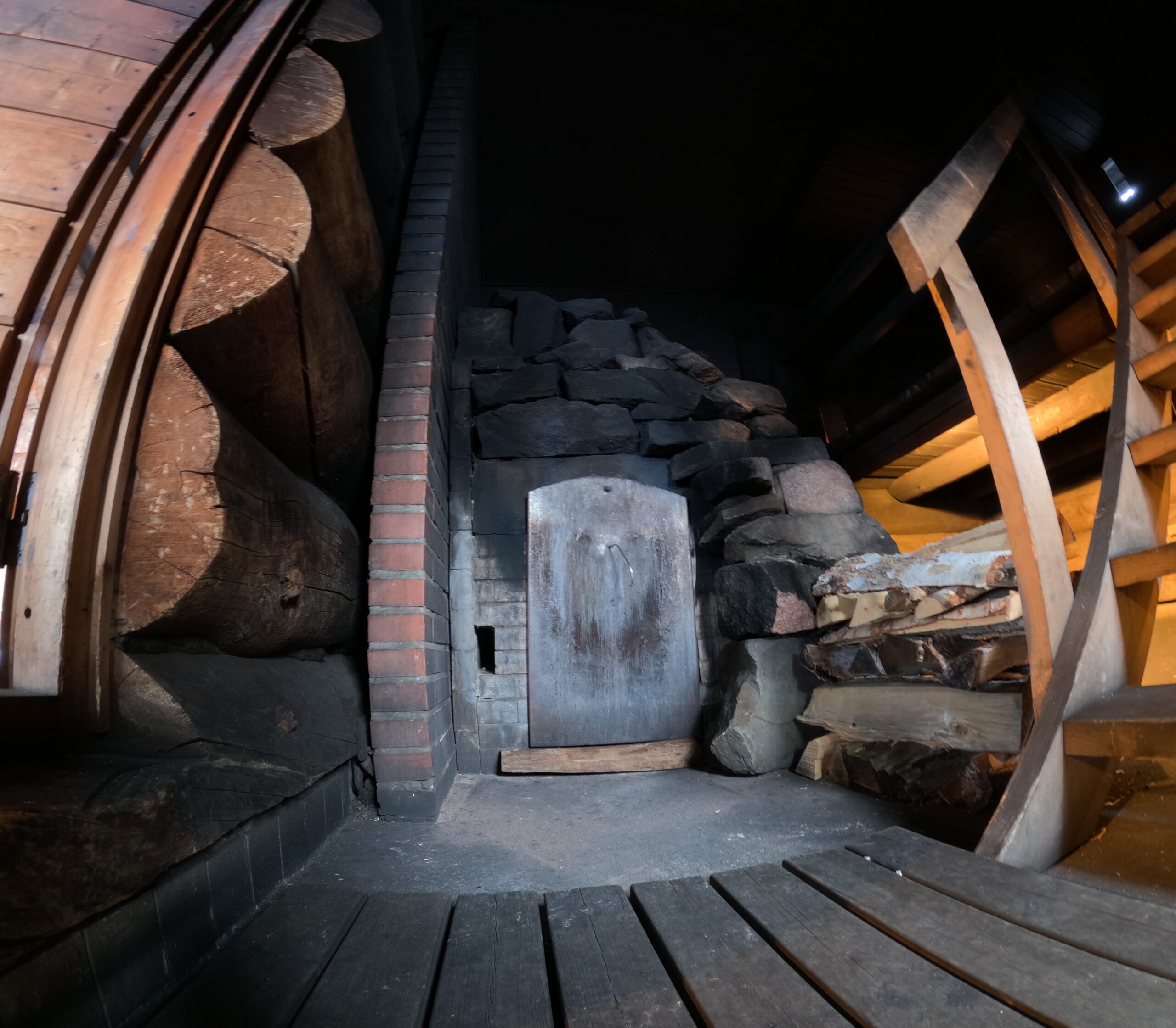 Kakslauttanen Arctic Resortスモークサウナ室内｜古材の丸太壁と石積みストーブ｜Saariselkä"