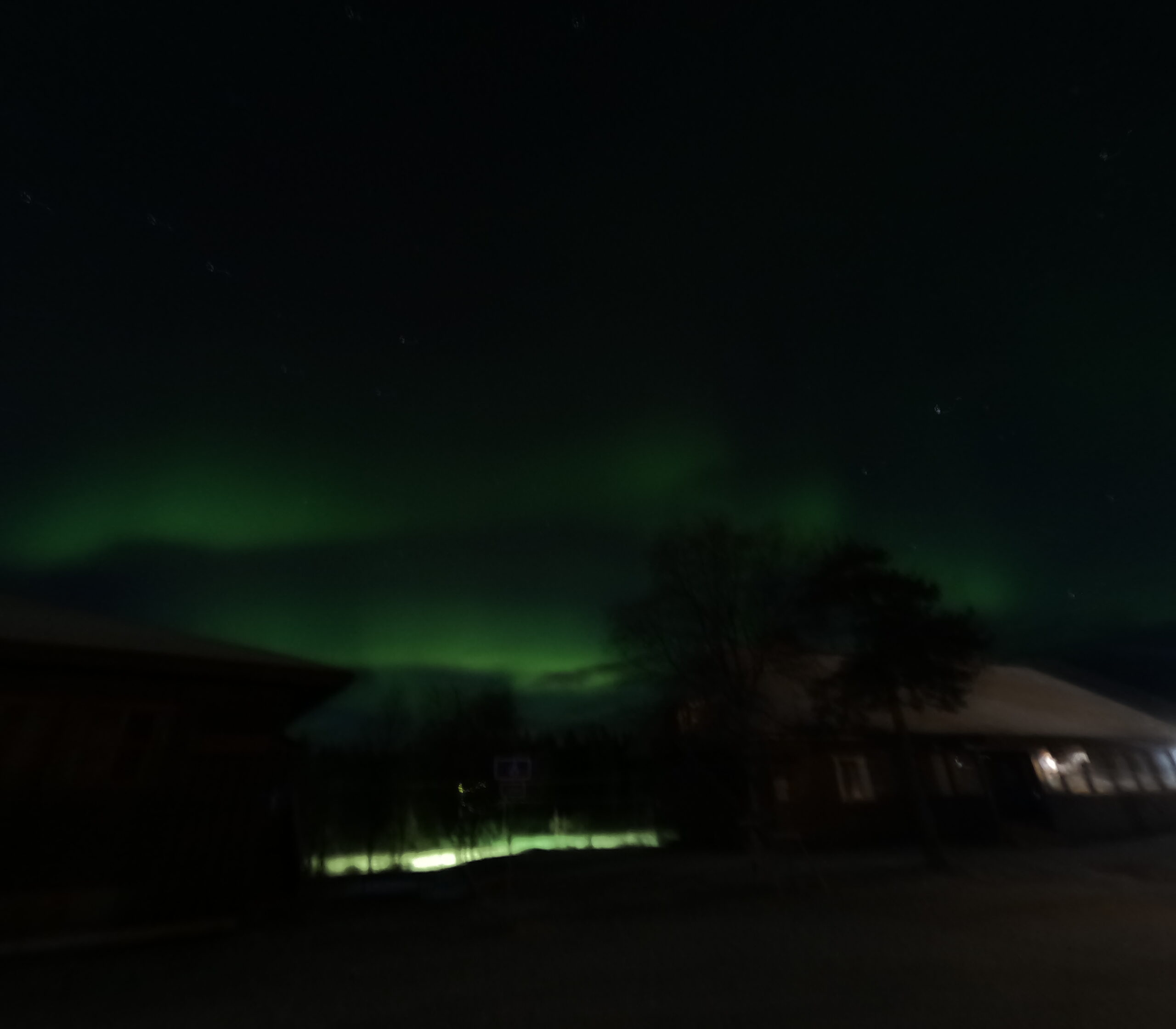 Kiilopää周辺の夜空に輝くオーロラ｜緑色の光のカーテンが夜空を彩り、雪原と施設のシルエットが浮かぶ神秘的な光景｜フィンランド・サーリセルカ