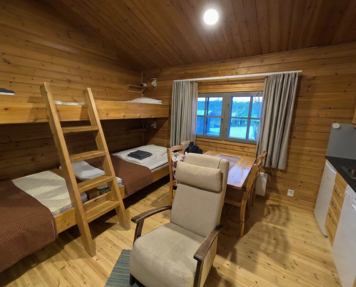 Kiilopääの宿泊室全景｜木製インテリアの二段ベッドと大きな窓から見える雪景色が特徴的な山小屋風の居心地の良い空間｜フィンランド・ラップランド地方