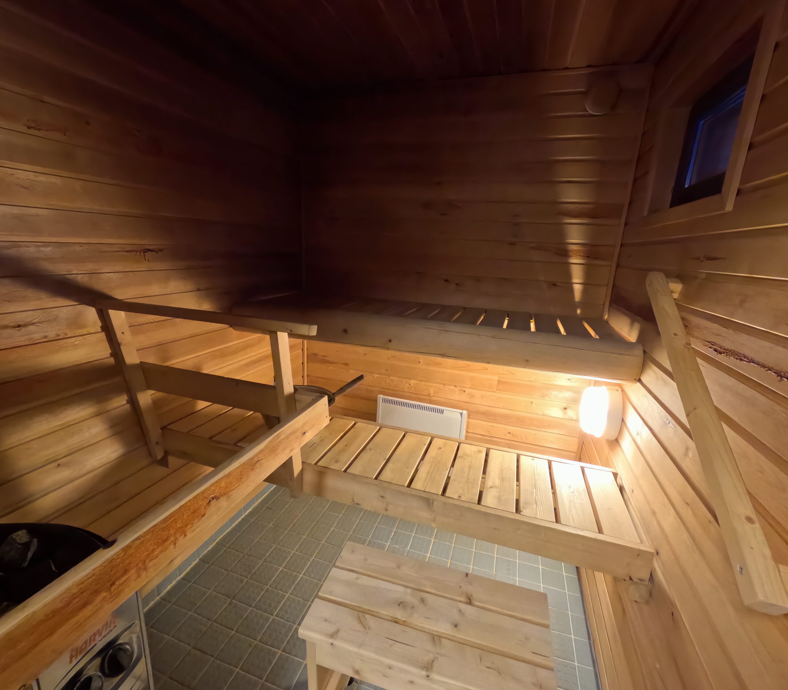 Kiilopääの宿泊施設に備え付けられた、サウナ室全体を映した木製ベンチと小窓のある内装｜温かみのある木材で統一されたリラックス空間｜フィンランド・ラップランド地方