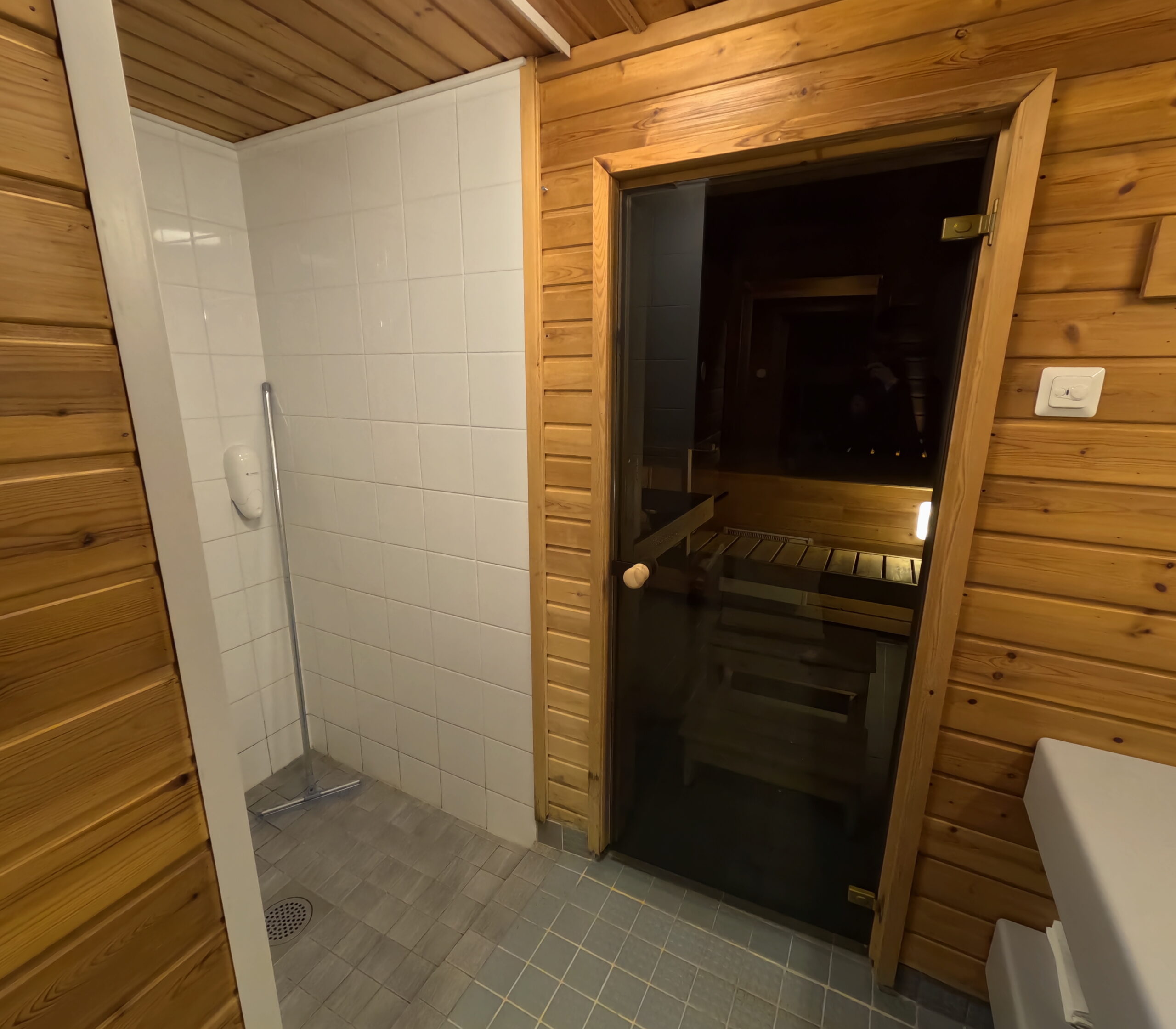 Kiilopääのサウナ施設内洗面所エリア｜明るい木製インテリアとサウナルームへのガラス扉が見える清潔で整然とした空間｜フィンランド・ラップランド地方