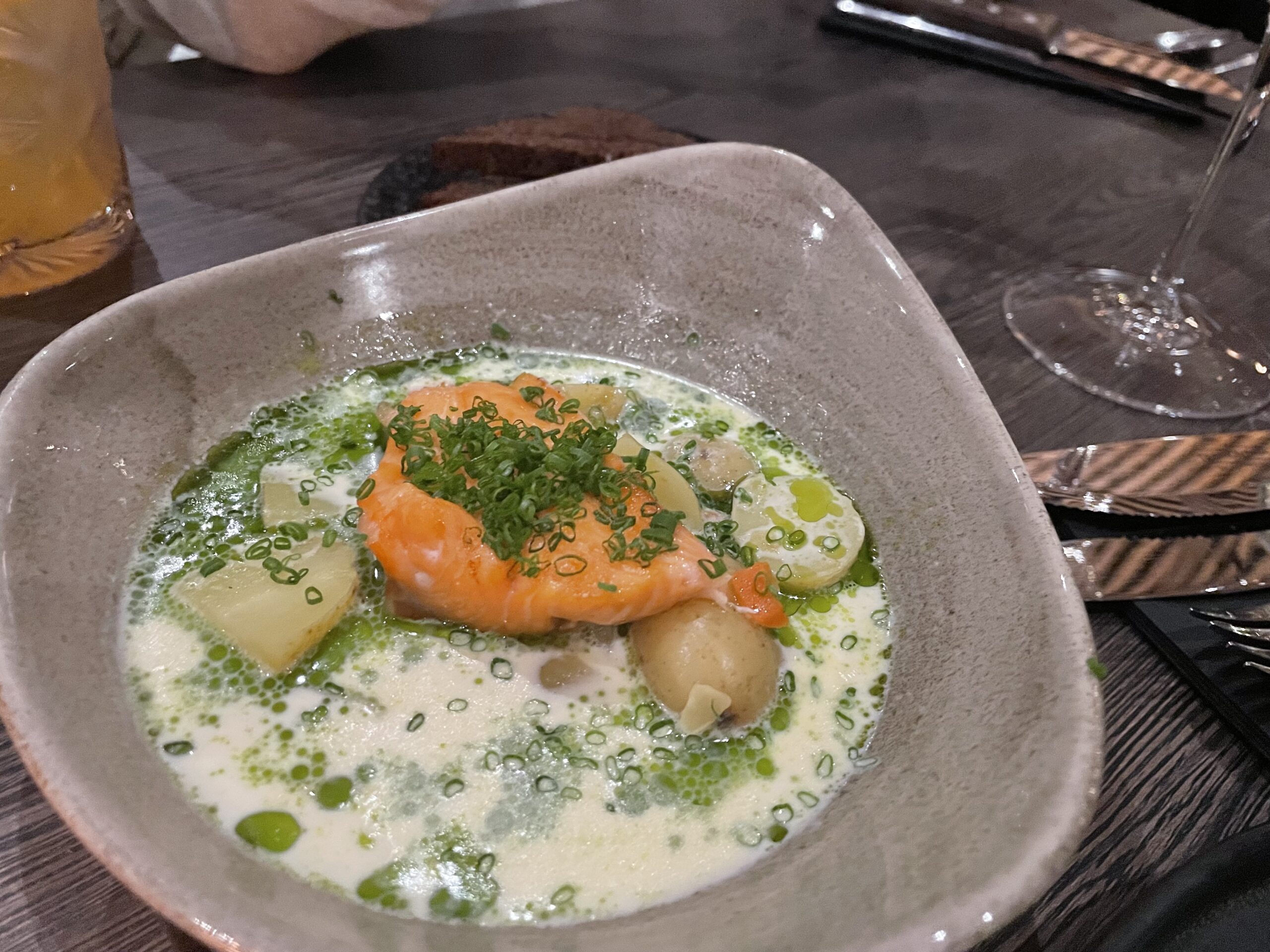 Kuumaレストラン料理｜白い皿に盛られたサーモンとポテト、クリームソースとハーブオイル、北欧スタイルの盛り付け、川沿いレストラン｜フィンランド・タンペレ