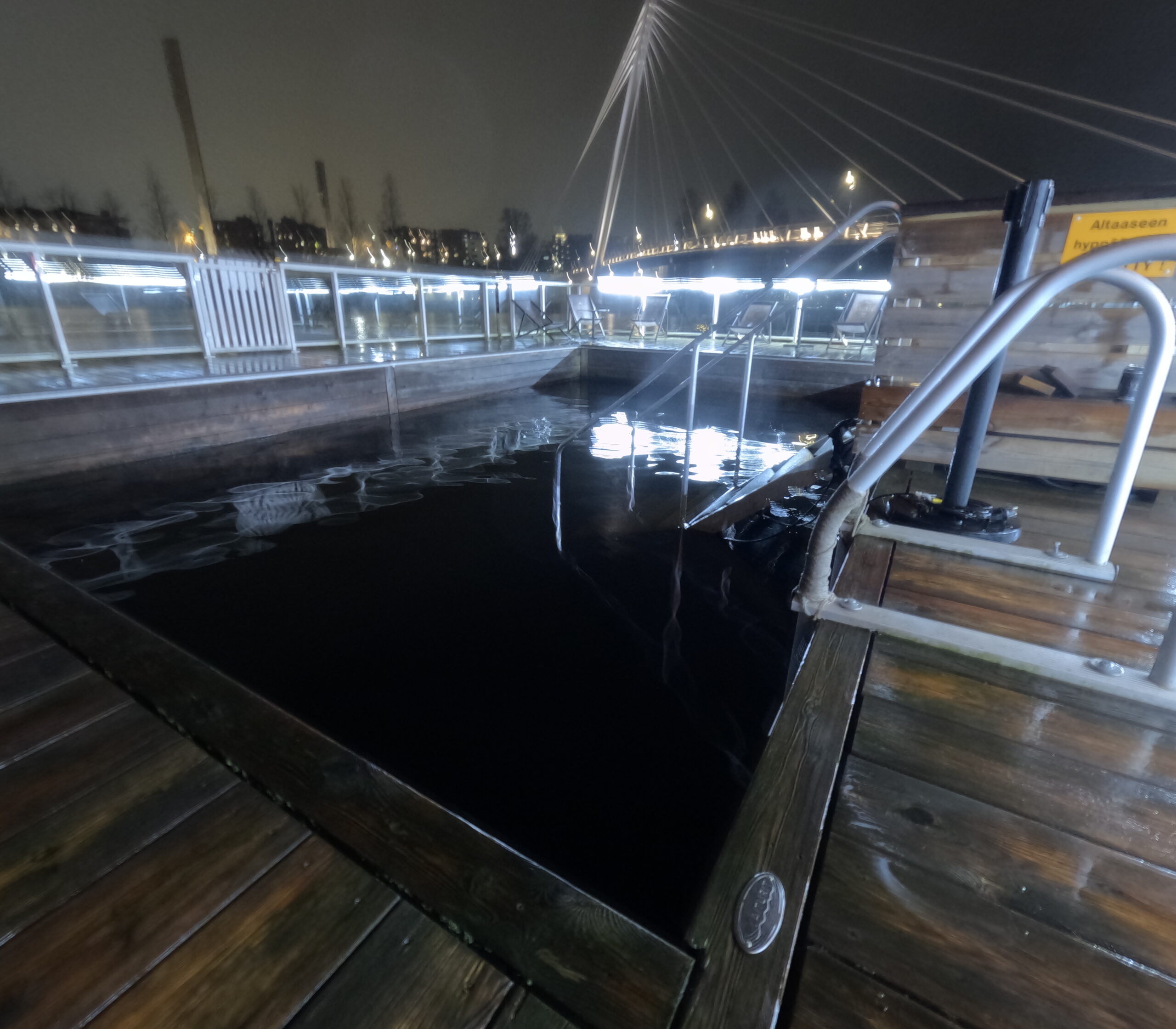 Kuuma川水風呂プール正面｜タンメルコスキ川に設置された長方形プール、ステンレス手すりと階段、ウッドデッキ、対岸の吊り橋と市街地夜景｜フィンランド・タンペレ