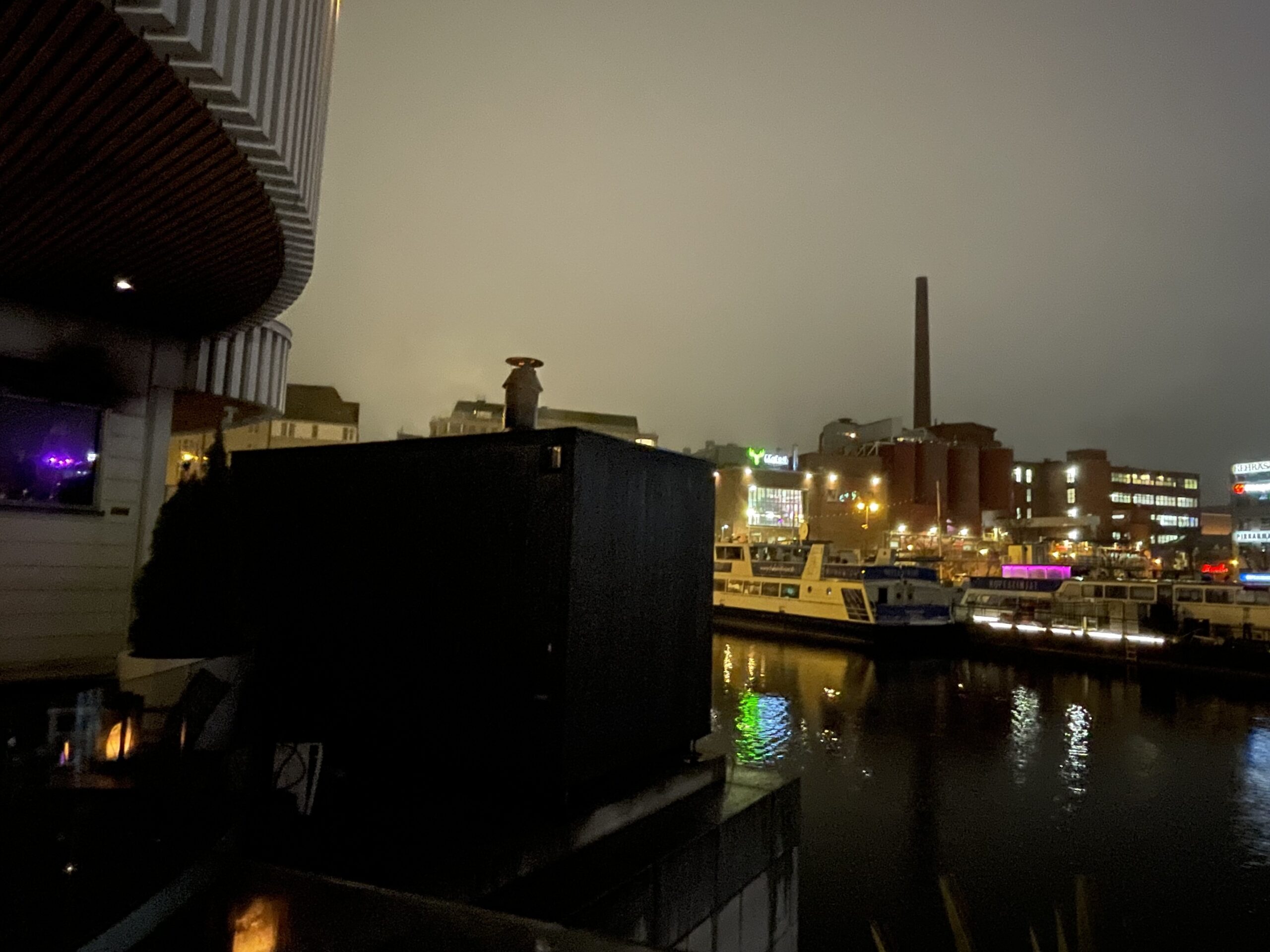 Kuuma夜景｜タンメルコスキ川沿いから見たタンペレ市街地、カラフルにライトアップされた建物群、川面に映る光、手すり付き桟橋｜フィンランド・タンペレ