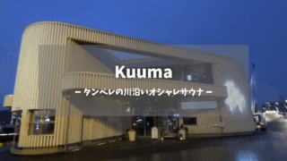 Kuuma（クーマ）アイキャッチ画像｜白い波型屋根の現代建築外観、「Kuuma - タンペレの川沿いオシャレサウナ」日本語テキストオーバーレイ、夕暮れの青空、ライトアップされた2階レストランテラス、Löyly姉妹店｜フィンランド・タンペレ