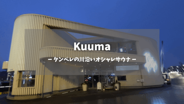 Kuuma（クーマ）アイキャッチ画像｜白い波型屋根の現代建築外観、「Kuuma - タンペレの川沿いオシャレサウナ」日本語テキストオーバーレイ、夕暮れの青空、ライトアップされた2階レストランテラス、Löyly姉妹店｜フィンランド・タンペレ