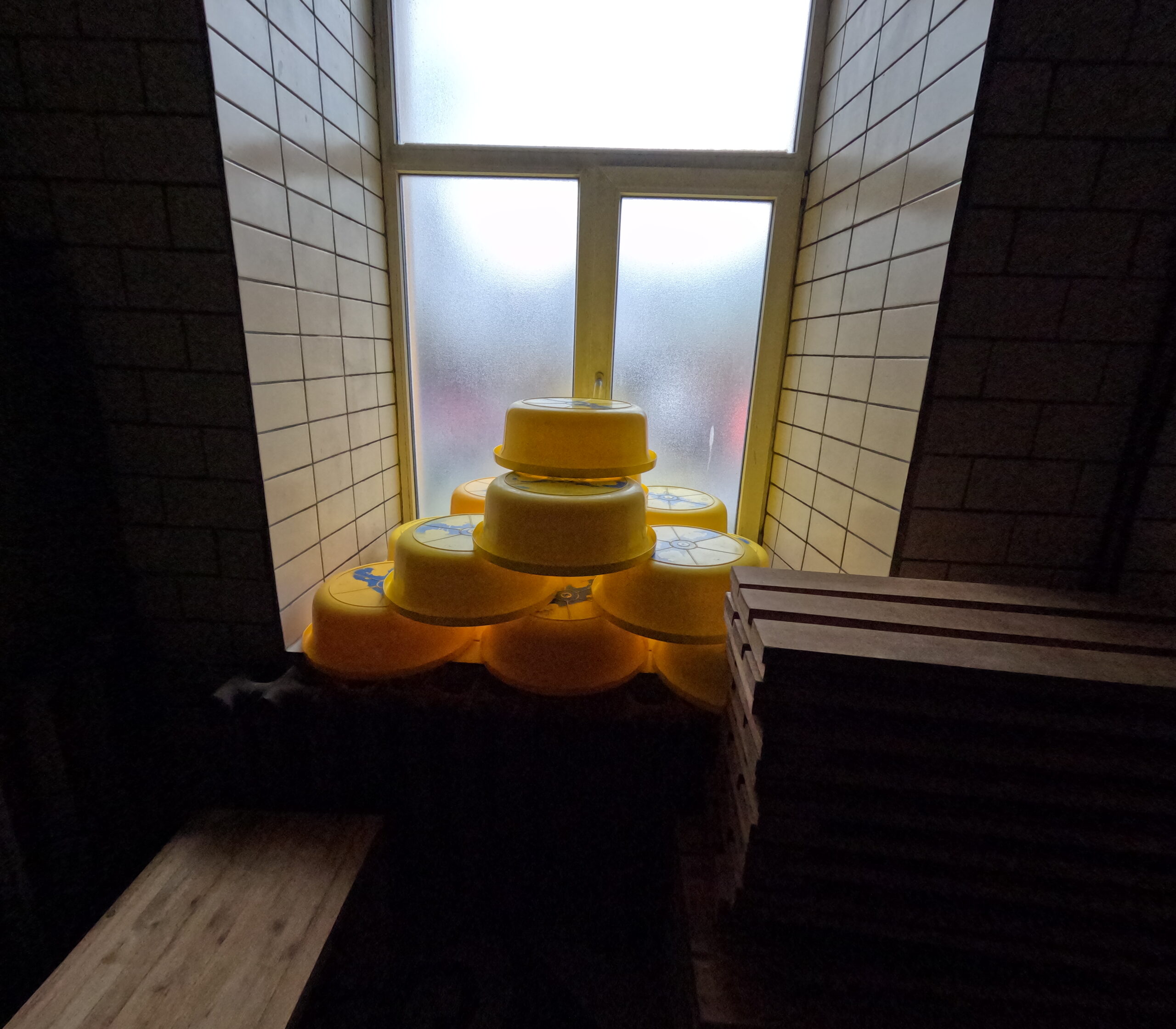 Leili Saunのウィスク用バケツ｜窓辺に並べられた黄色い容器セット、自然光に照らされた伝統的なサウナ用品｜タリン・エストニア