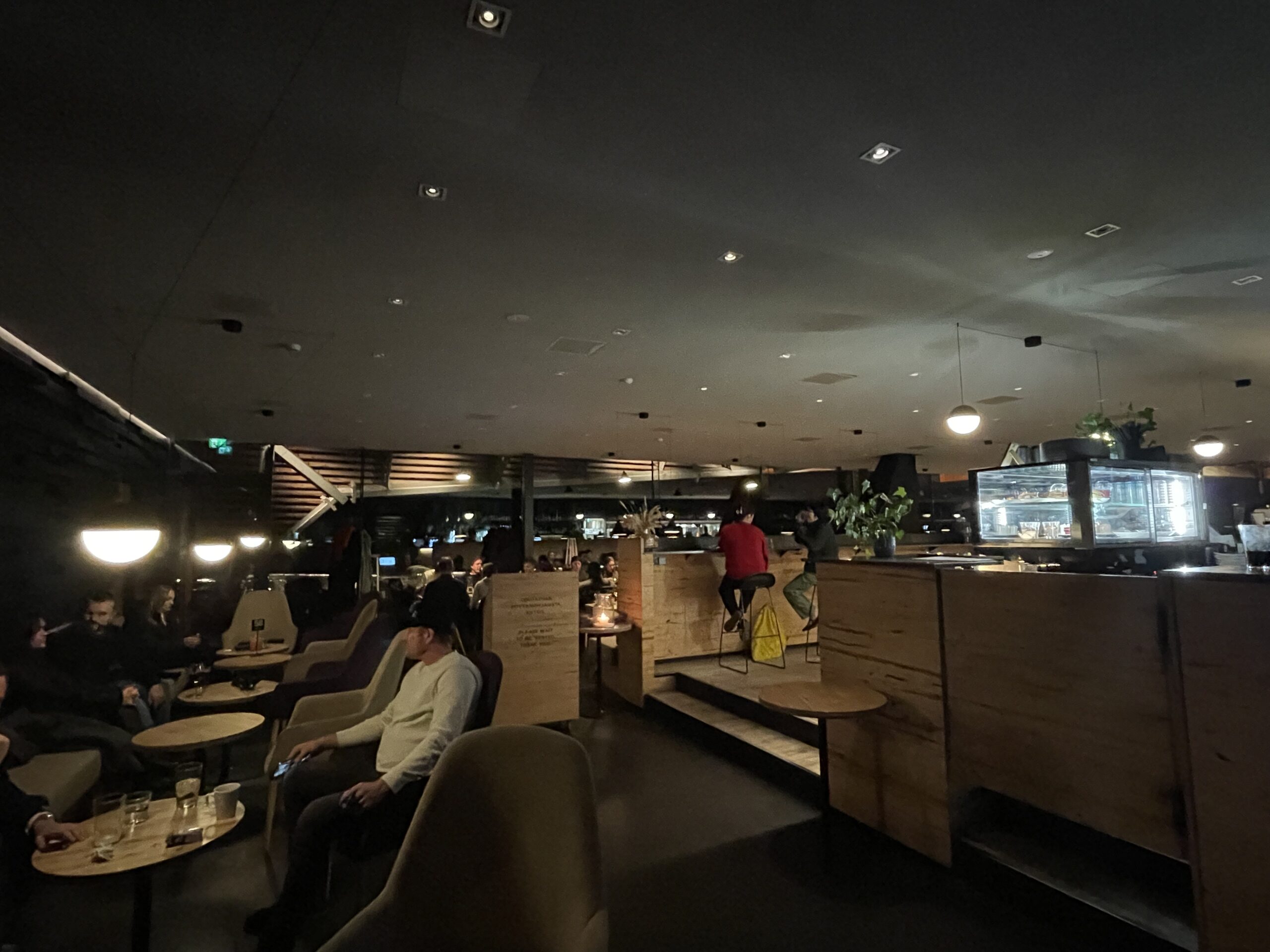 löylyヘルシンキのコモンエリア休憩室｜暖炉と木製家具が配置された北欧デザインの落ち着いた空間、ソファでくつろぐ利用客たち、暗めの照明で温かみのある雰囲気｜フィンランド・ヘルシンキ