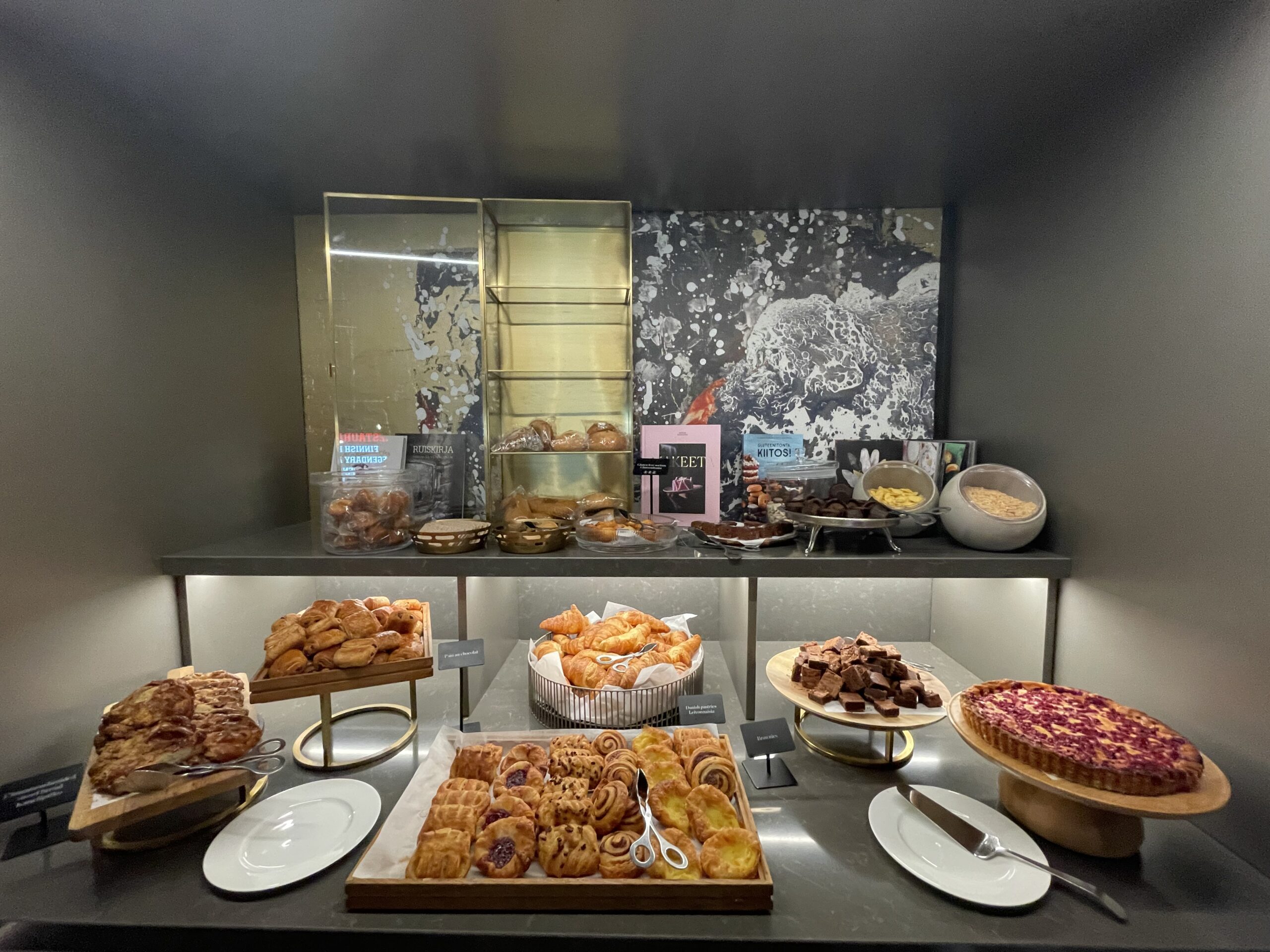 NH Collection Helsinki Grand Hansa朝食ビュッフェのペストリーコーナー｜クロワッサン・デニッシュ・ベリータルトが並ぶ洗練されたディスプレイ、温かい照明と金属製の棚が高級感を演出｜ヘルシンキ中央駅前・フィンランド