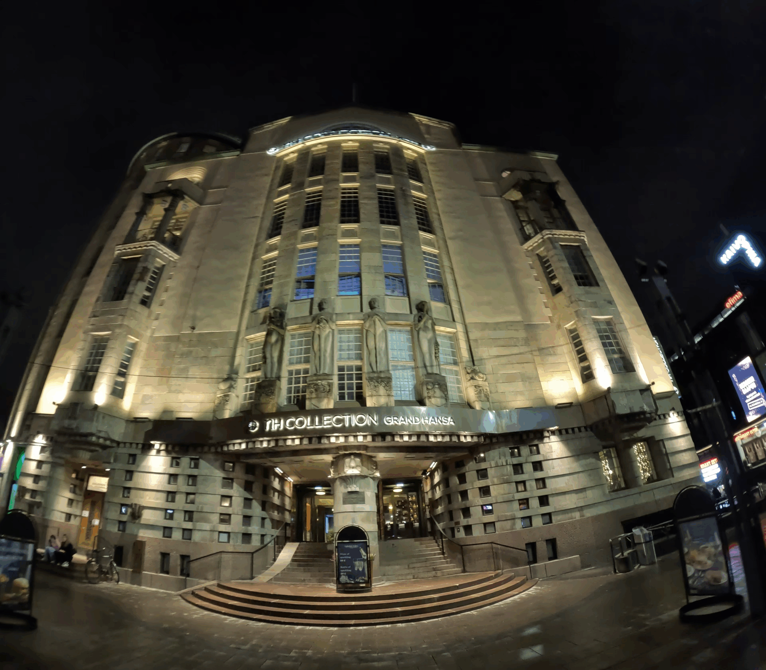 NH Collection Helsinki Grand Hansa外観｜歴史的建築の夜景、アールデコ様式のファサード・彫刻装飾・温かいライトアップが威厳ある佇まいを演出、ヘルシンキ中央駅正面の堂々たるエントランス｜フィンランド